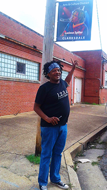 Lucious Spiller under his sign in Clarksdale's historic downtown Arts & Culture District.